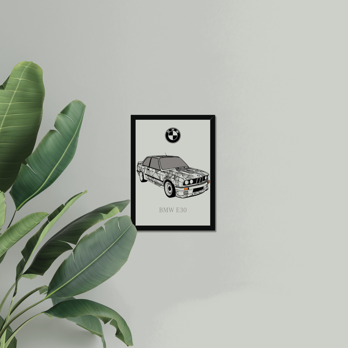 BMW E30 black-framed print beside large green leaves